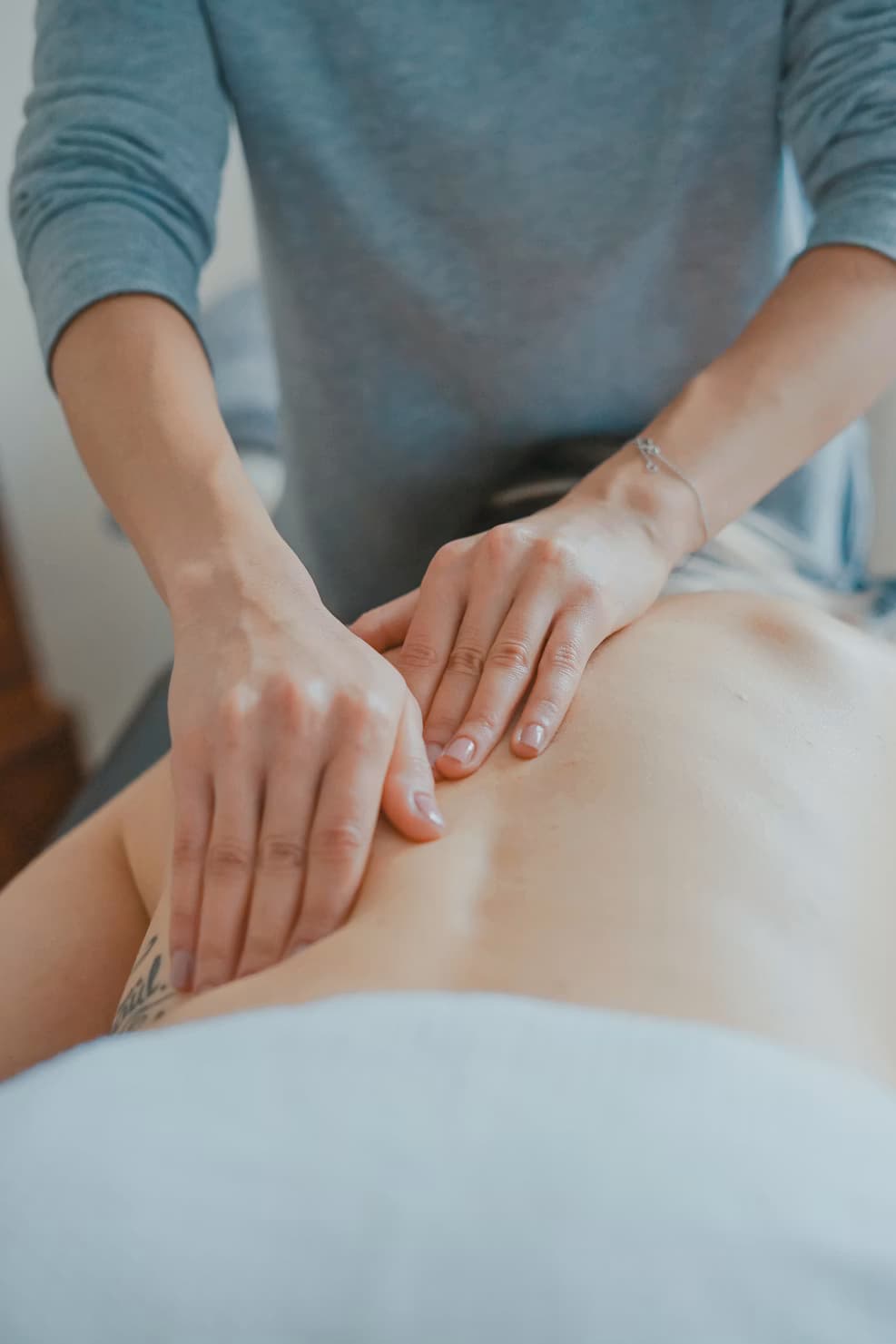 Massageterapeut, händer på rygg, naturligt sidoljus